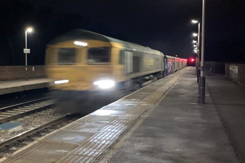 Freight train speeds through a station at night