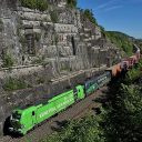 Image of intermodal train in deep gorge in Bavaria being hauled by bright green locomotive
