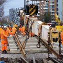 Engineers in orange suits with crane laying track