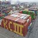 Drong picture of a stack of shipping containers, coloured red and yellow and arranged to say "KC III"