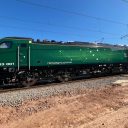 Class 93 tri-mode locomotive in green livery for Rail Operations Group standing on barren ground in Spain, ready for delivery to UK