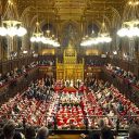 Wide shot of the House of Lords with the King and Queen in attendance for the State opening of Parliament. Full of lords in regal dress