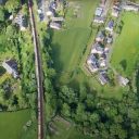 Overhead shot of a long freight train travelling through village and countryside