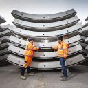 Two engineers standing in front of a stack of huge prefabricated tunnel segments