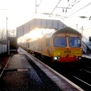 Freight train passing under footbridge with sunset in background